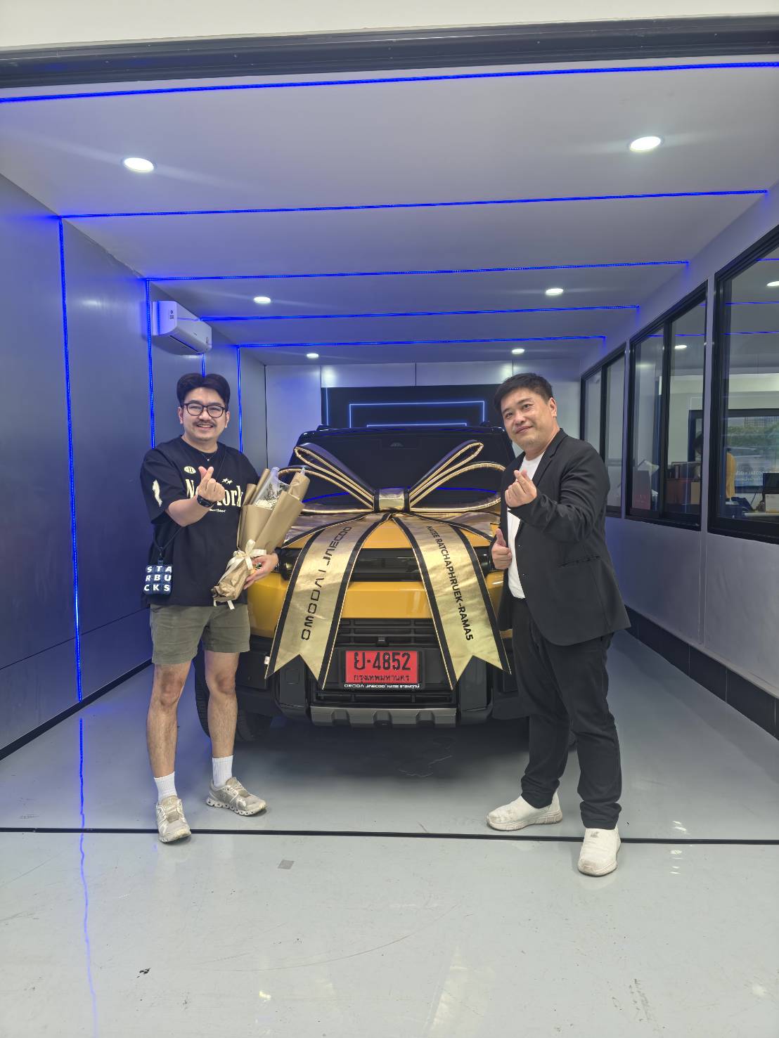ลูกค้ารับมอบรถสีเหลืองตกแต่งด้วยโบว์ที่โชว์รูม